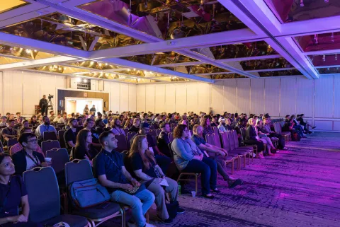 A crowd under the venue's lit ceiling during React Miami 2025.