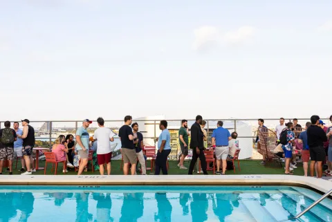 Attendees mingling around a rooftop pool at dusk.